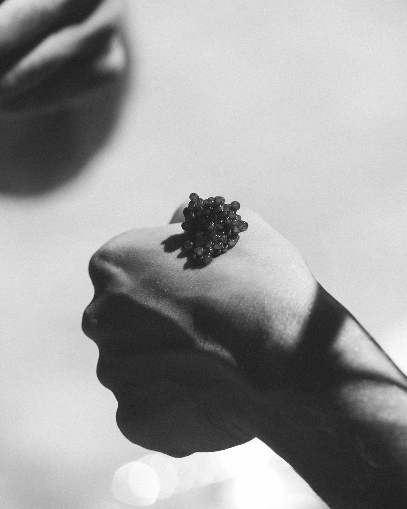Caviar pearls tasted from the hand - the traditional ritual of savouring sturgeon roe, La Caviare