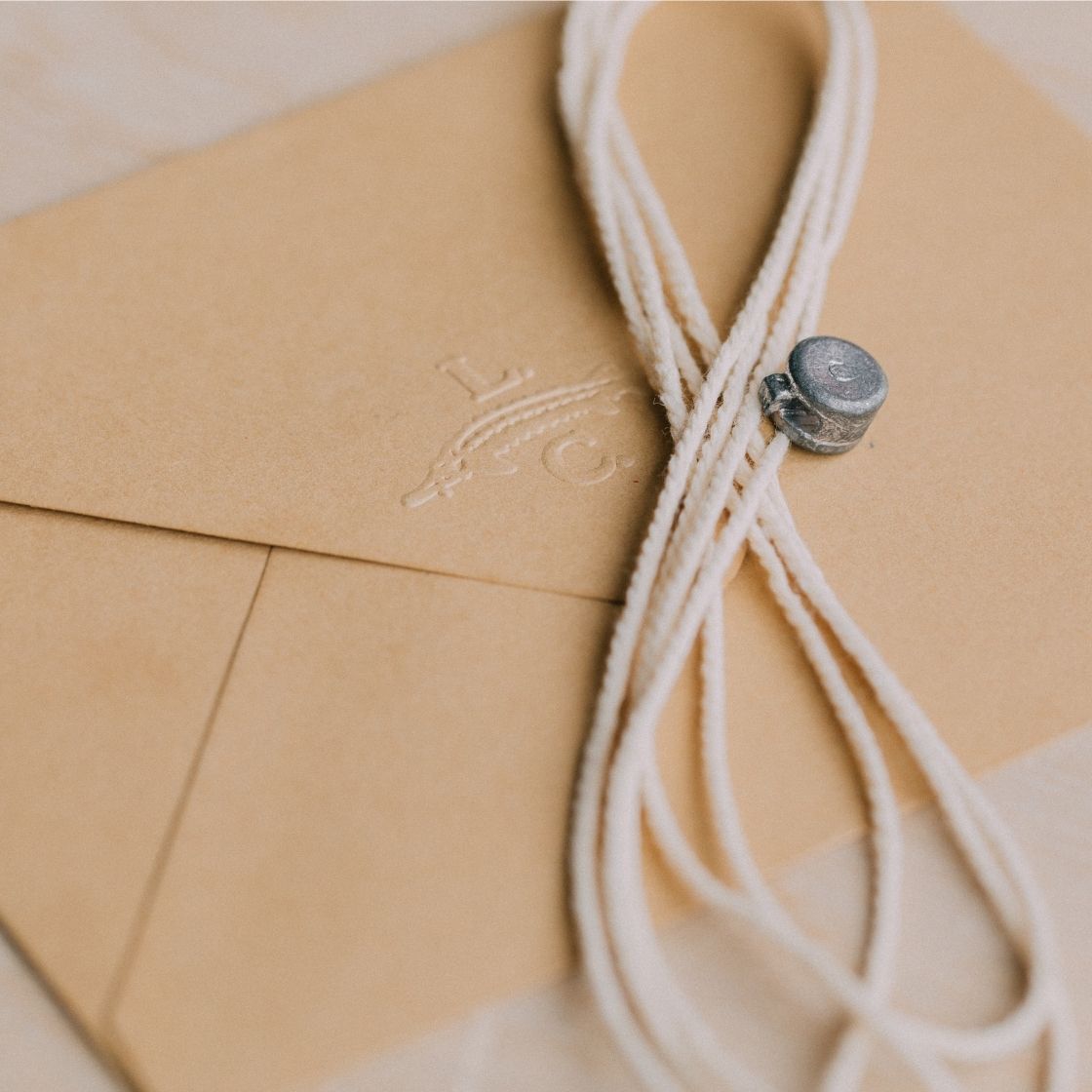 Beige envelope with a decorative string and button, featuring an La Caviare logo.