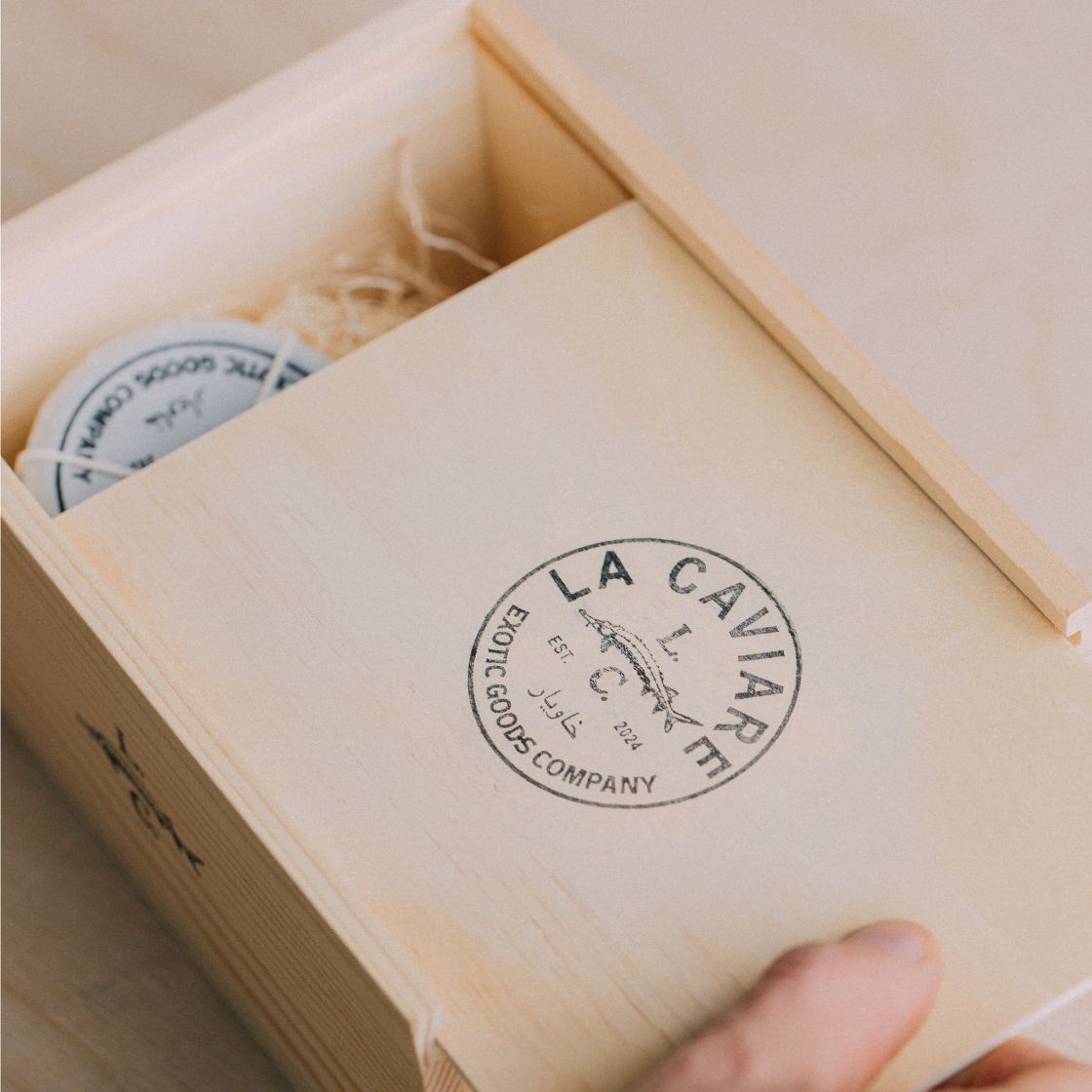 Open wooden box with 'La Caviare' branding and caviar tins inside a box.

